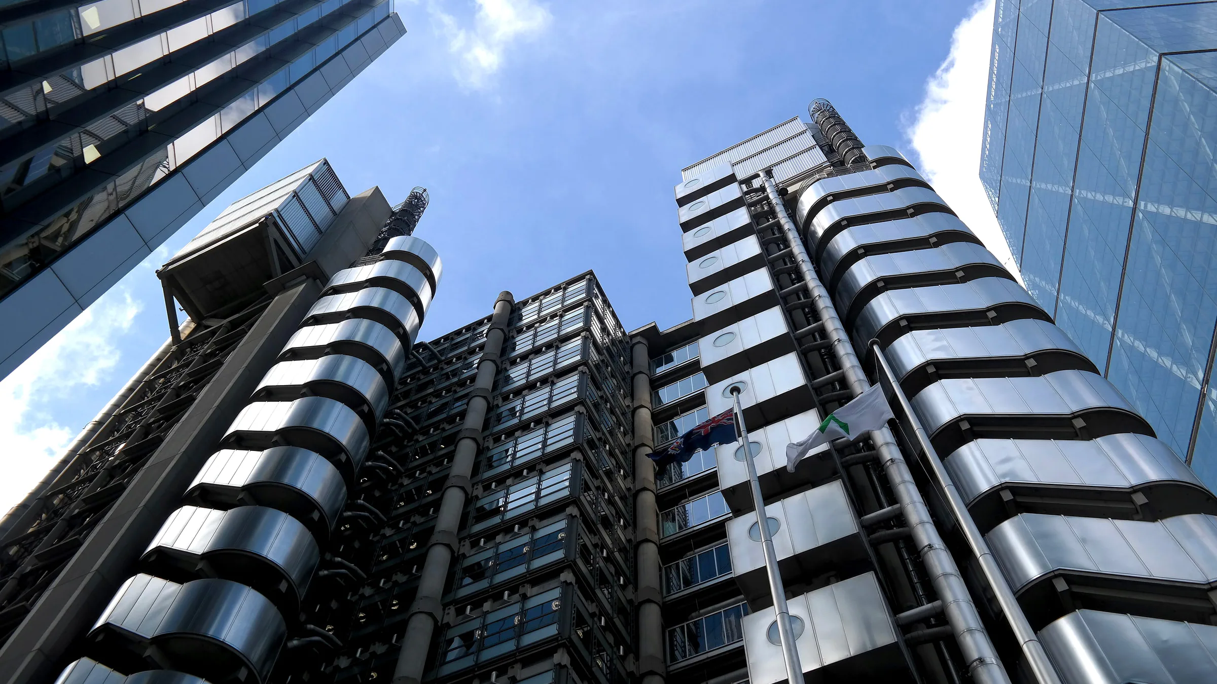 Looking up at the steel stair towers and pipes of the Lloyd's building in the City of London, between glass office towers