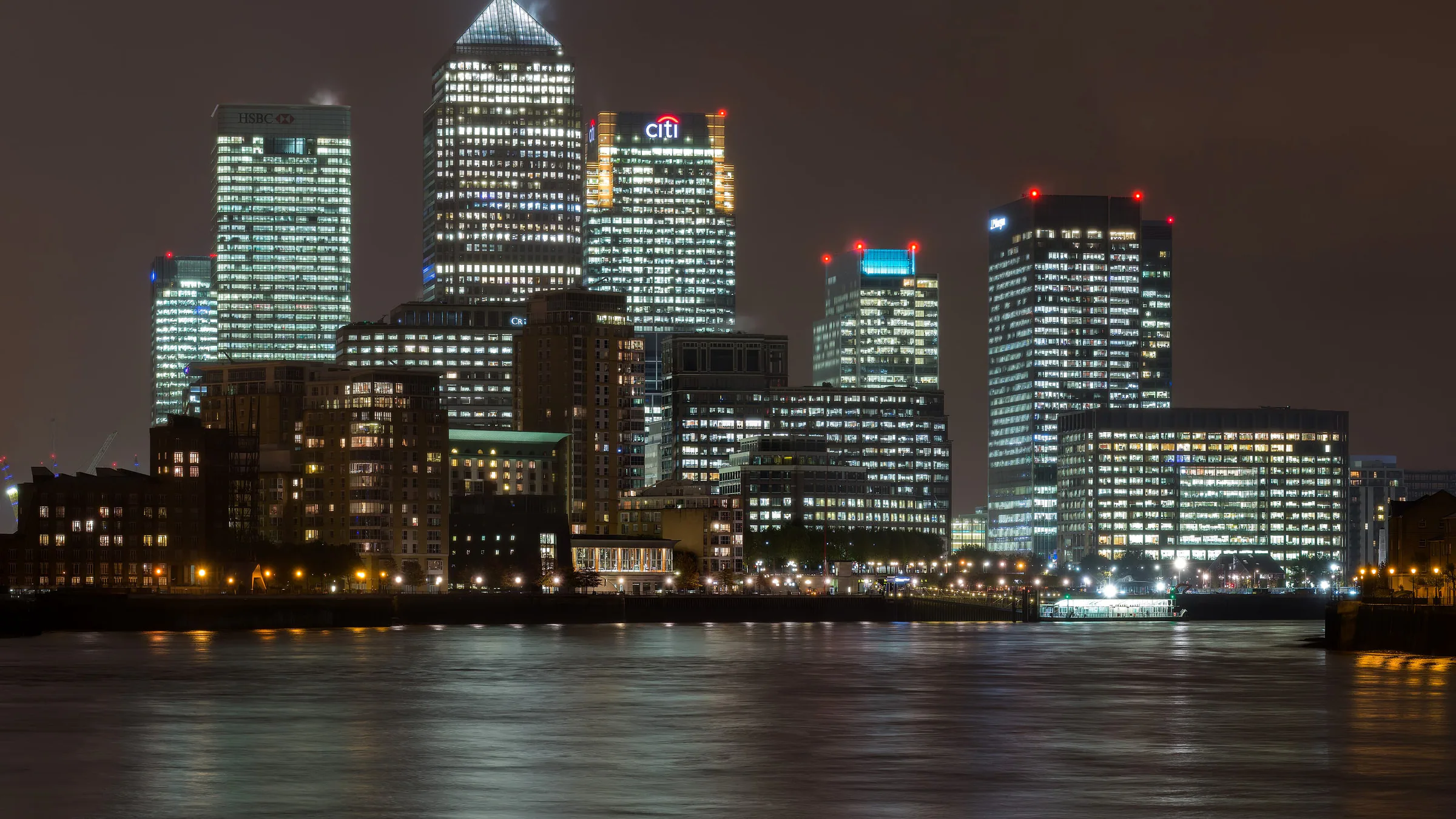 The lit towers of Canary Wharf reflected in the Thames at night